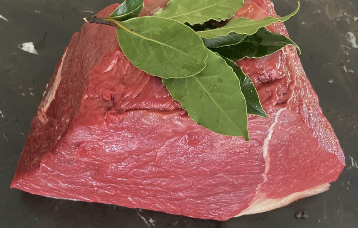 Rohes Bratenstück vom Rind mit Lorbeerblättern auf dunklem Stein