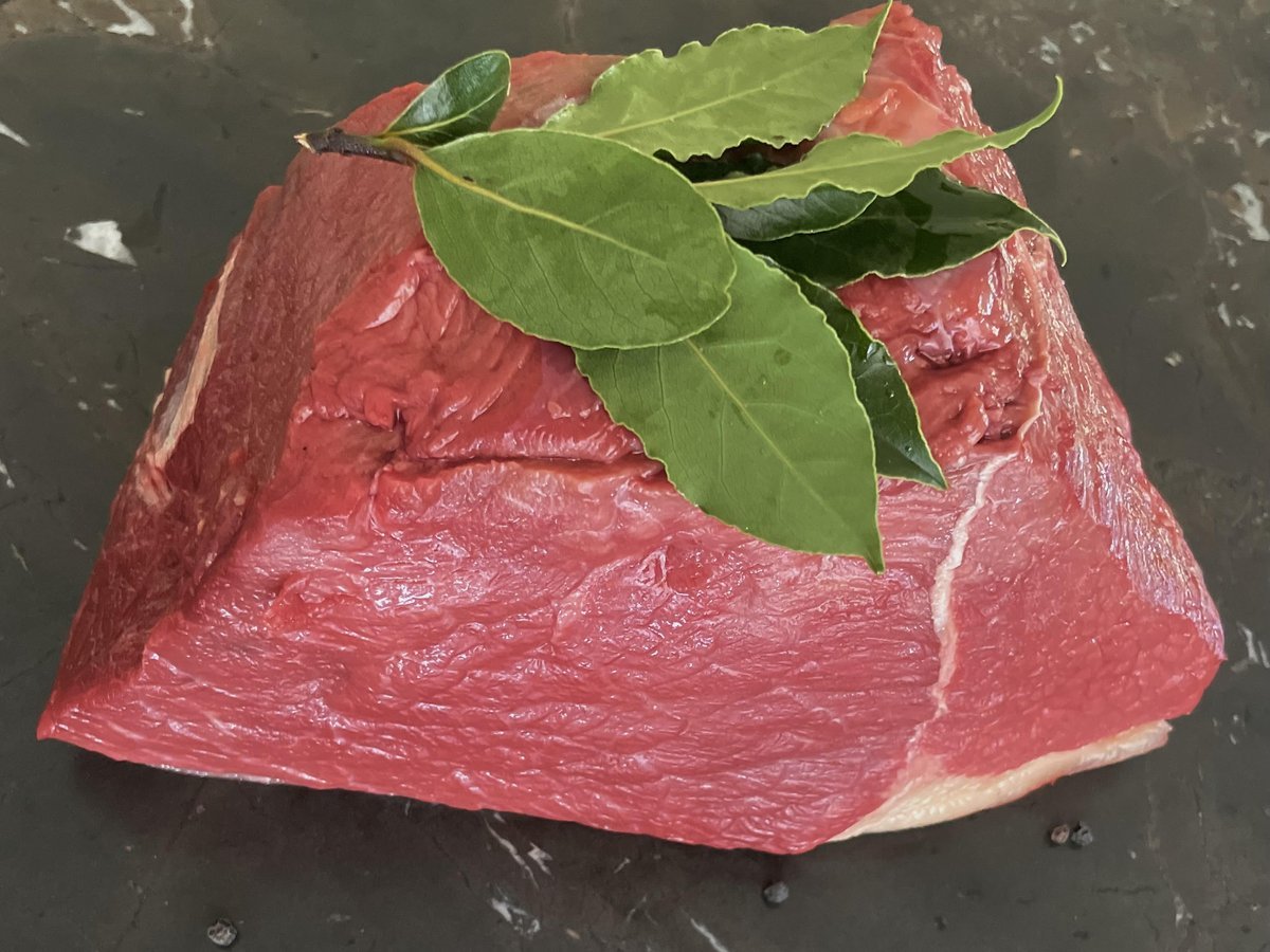 Rohes Bratenstück vom Rind mit Lorbeerblättern auf dunklem Stein