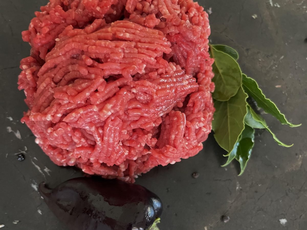 Rohes Rinderhackfleisch auf dunklem Stein mit Lorbeerblättern