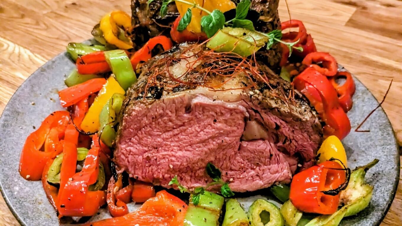 Rosa gebratener Rinderbraten, angeschnitten, auf Ofengemüse mit Paprika